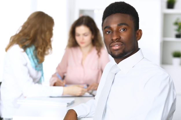 Homme d'affaires afro-américain lors d'une réunion sur fond de bureau de couleur blanche