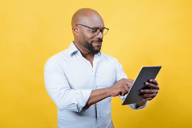 homme d'affaires afro-américain manipulant la technologie sur fond jaune