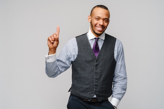 Homme d'affaires afro-américain montrant un doigt sur un mur gris