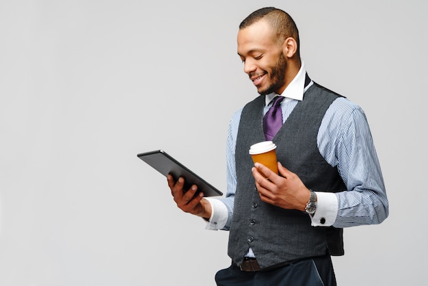 Homme d'affaires afro-américain professionnel tenant un tablet pc et une tasse de café.