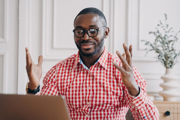 Homme d'affaires afro-américain ravi dans des verres lisant de bonnes nouvelles sur un ordinateur portable sur le lieu de travail