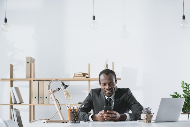 Un homme d'affaires afro-américain souriant utilisant un smartphone