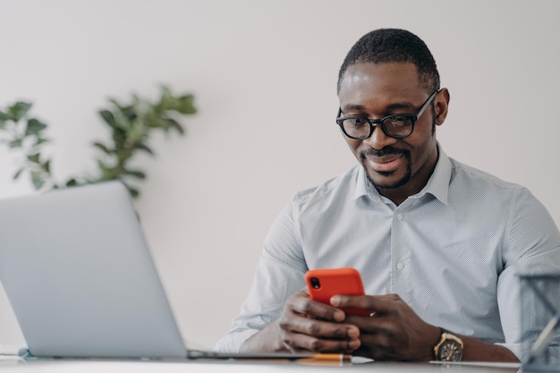 Un homme d'affaires afro-américain tenant un téléphone utilise des applications pour le commerce électronique travaillant en ligne