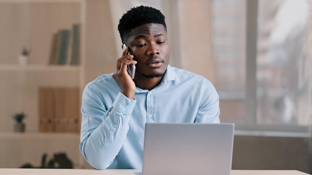 Un homme d'affaires afro-américain travailleur indépendant parle de bavardage sur un téléphone portable avec la marque du client