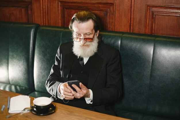 Homme d'affaires âgé barbu. Homme avec du café. Senior en costume noir.