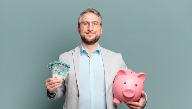 Homme d'affaires d'âge moyen avec de l'argent et une tirelire