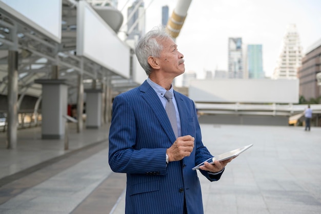 Homme d'affaires d'âge moyen mature senior asiatique utilisant une tablette dans la ville moderne