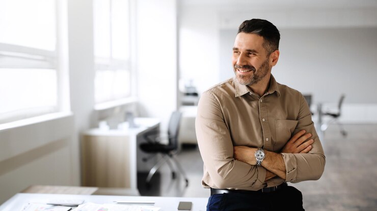 Photo homme d'affaires d'âge moyen prospère posant avec les mains croisées regardant loin et souriant copie espace