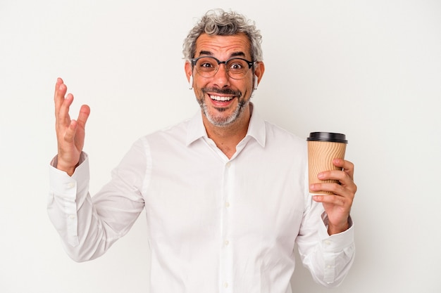 Homme d'affaires d'âge moyen tenant un café à emporter isolé sur fond blanc recevant une agréable surprise, excité et levant les mains.