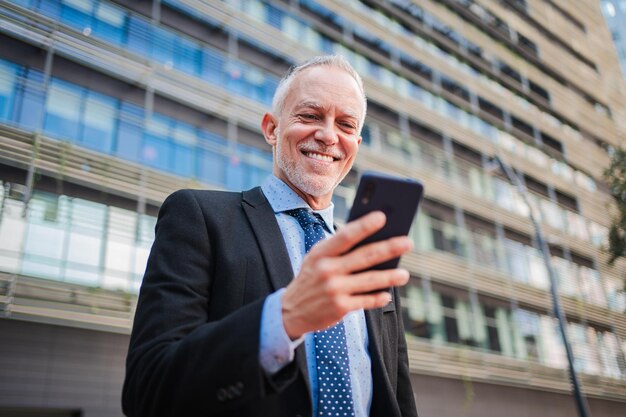 Photo un homme d'affaires d'âge moyen utilisant un téléphone portable pour surveiller ses finances en dehors d'un homme d'affaires mature