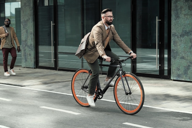 Homme d'affaires d'âge mûr à cheval pour son travail à vélo le long des rues de la ville