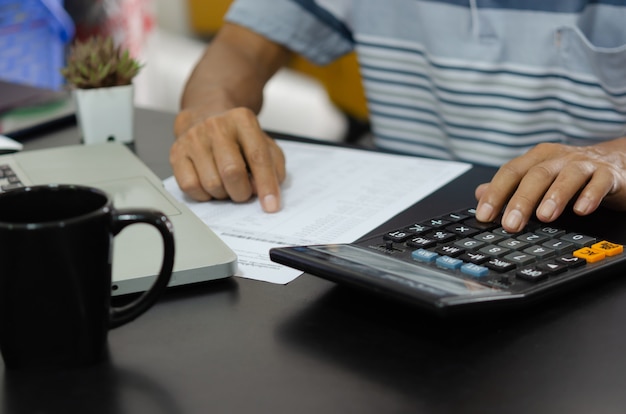 Homme d'affaires à l'aide de la calculatrice à un bureau. Concepts de finance d'entreprise, de fiscalité et d'investissement.