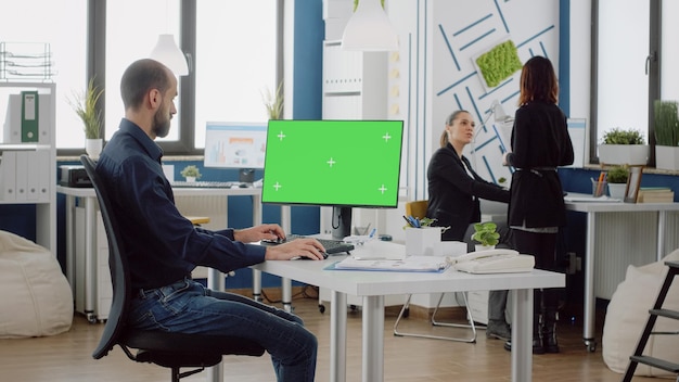 Homme d'affaires à l'aide d'un clavier et d'un écran vert horizontal sur moniteur au bureau de l'entreprise. Homme avec un travail d'entreprise regardant la clé chroma sur ordinateur avec modèle et arrière-plan de maquette isolés