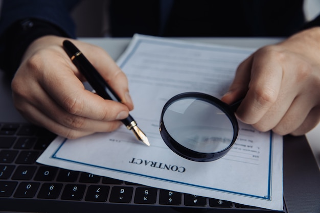 Homme d'affaires à l'aide d'une loupe pour signer un contrat