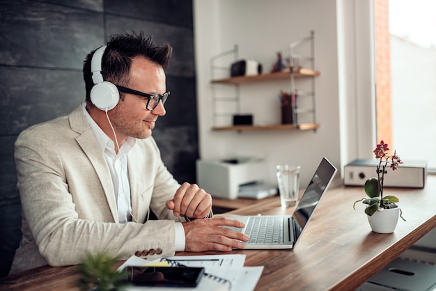 Homme d'affaires à l'aide d'un ordinateur portable et écoute de la musique au casque