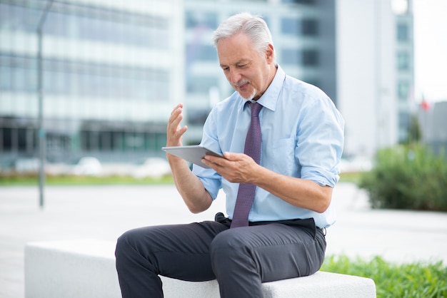 Homme d'affaires à l'aide de sa tablette en plein air