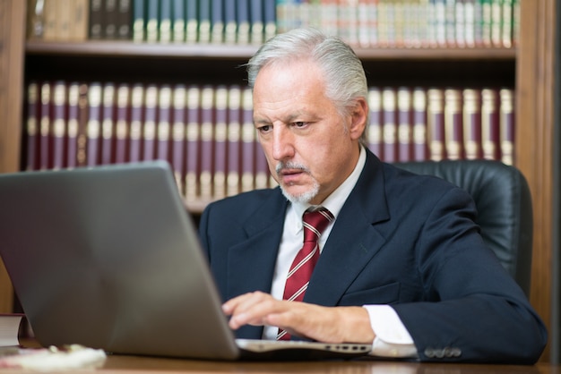 Homme d'affaires à l'aide de son ordinateur portable dans une bibliothèque