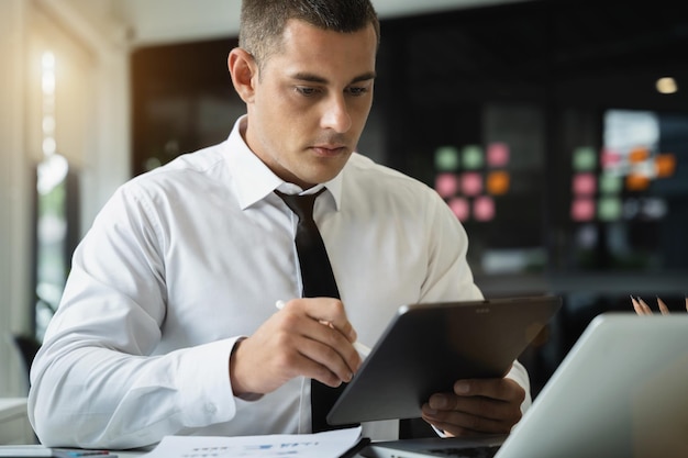 Homme d'affaires à l'aide d'une tablette et d'un ordinateur pour analyser les finances de l'entreprise graphique au bureau