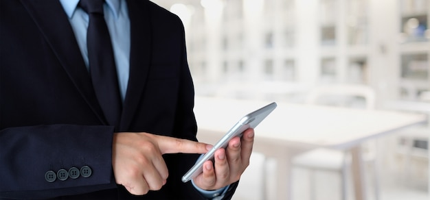 Homme d&#39;affaires à l&#39;aide de téléphone intelligent sur fond de bureau flou