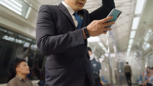 Homme d'affaires à l'aide de téléphone mobile dans le train public. Concept de transport urbain de style de vie de la ville.