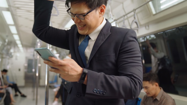 Homme d'affaires à l'aide de téléphone mobile dans le train public. Concept de transport urbain de style de vie de la ville.