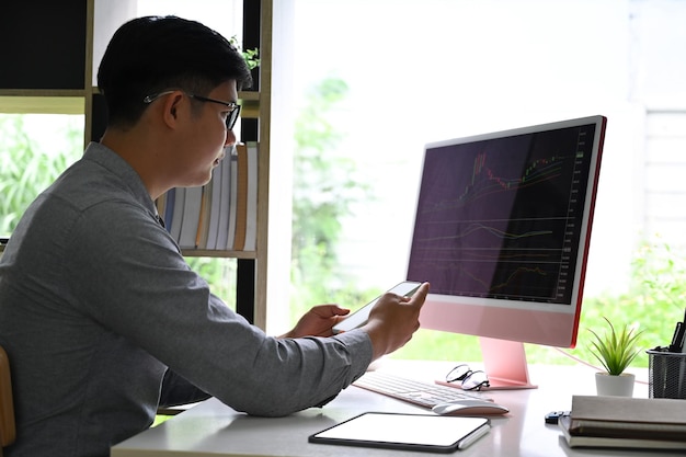 Homme d'affaires analysant des données statistiques sur l'écran de l'ordinateur au bureau
