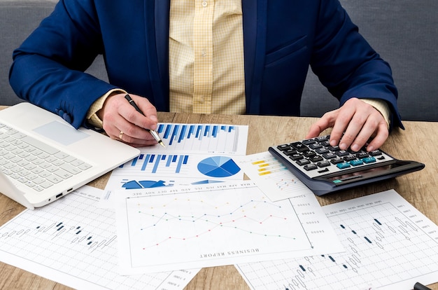 Homme d'affaires analysant des graphiques et des diagrammes sur une table en bois