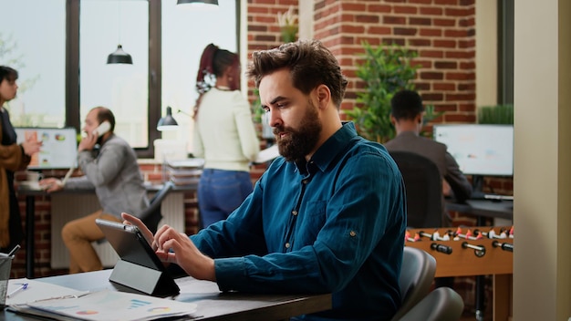 Homme d'affaires analysant des informations de recherche sur une tablette numérique, utilisant des données pour planifier la présentation. Employé masculin travaillant sur le rapport d'une entreprise en démarrage et trouvant des idées pour la gestion d'entreprise.