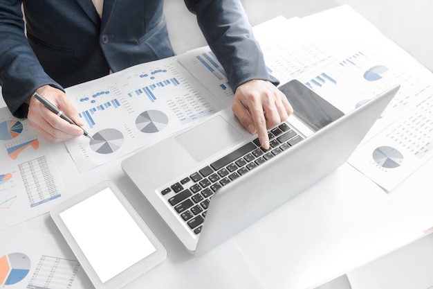 Un homme d'affaires analyse des graphiques et utilise un ordinateur portable à son bureau.