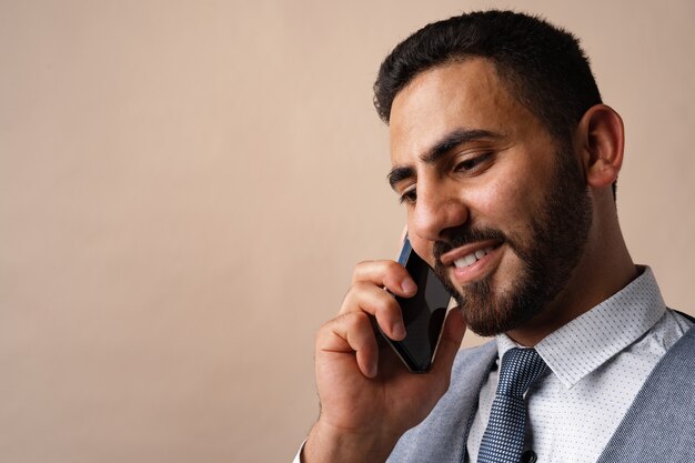 Homme d'affaires arabe parlant sur son téléphone portable sur fond beige