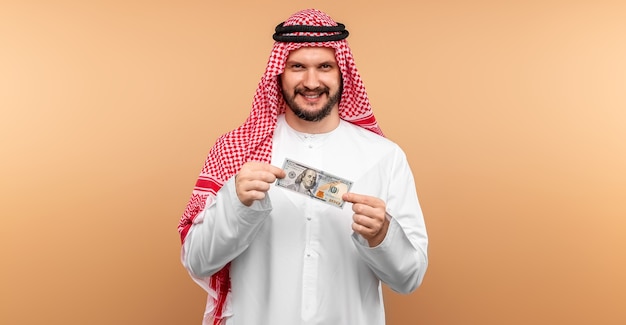 Homme d'affaires arabe en tenue nationale se réjouit des dollars dans ses mains, grand profit.