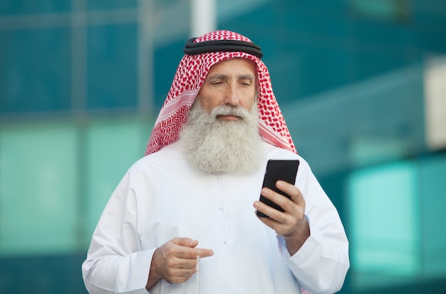 Homme d'affaires arabe travaillant avec son téléphone dans une rue en arrière-plan