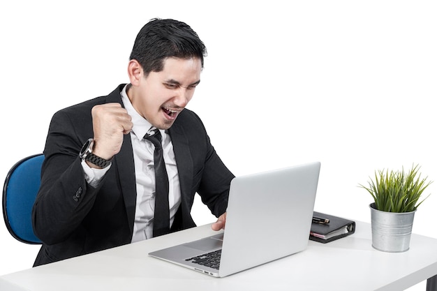 Homme d'affaires asiatique assis avec un ordinateur portable sur le bureau avec une expression réussie