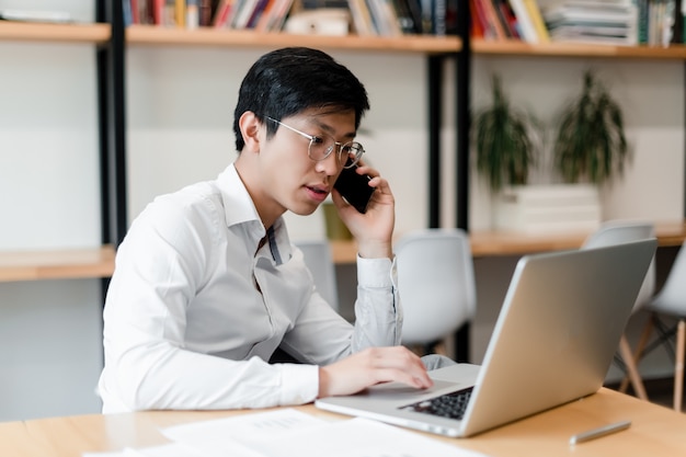 Homme d'affaires asiatique au bureau fonctionne avec un ordinateur portable