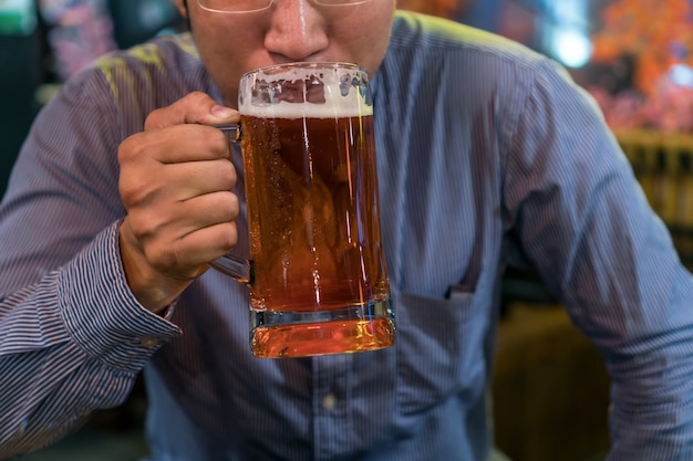 Homme d&#39;affaires asiatique dans l&#39;action de bonheur et de boire de la bière après le travail ou le travail de succès