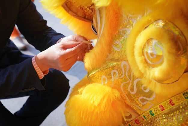 Un homme d'affaires asiatique décore un lion de Chine jaune artefact en couvrant une plaque d'or à son œil