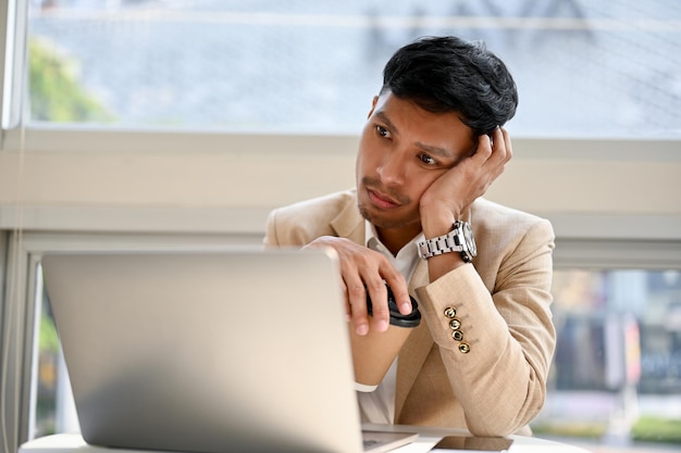 Homme d'affaires asiatique ennuyé et fatigué travaillant sur son projet sur ordinateur portable travaillant à distance au café