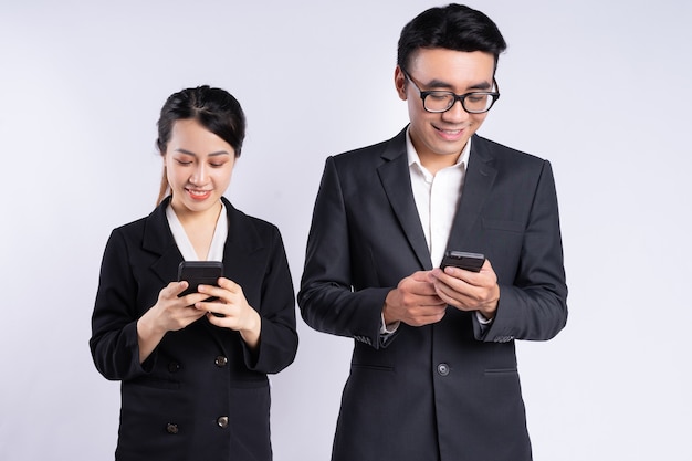 Homme d'affaires asiatique et femme d'affaires utilisant un smartphone sur fond blanc