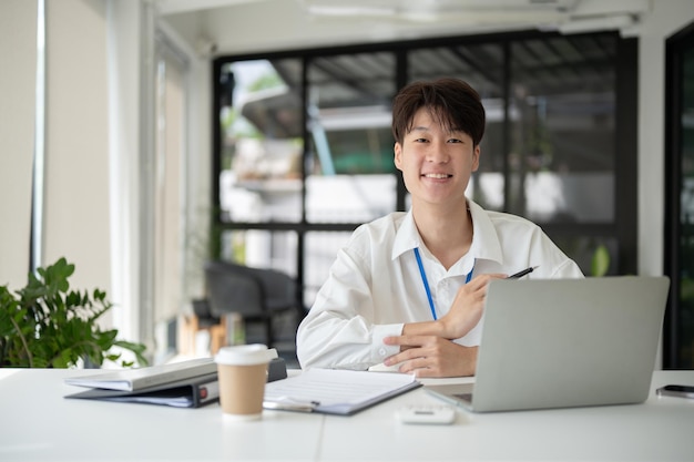 Un homme d'affaires asiatique intelligent ou un employé de bureau masculin est assis à son bureau dans un bureau moderne