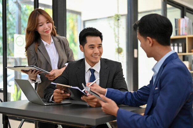 Homme d'affaires asiatique intelligent parlant et travaillant avec ses employés financiers au bureau