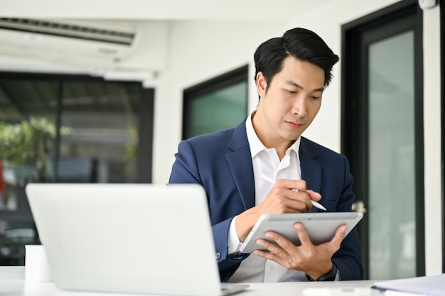 Homme d'affaires asiatique intelligent utilisant sa tablette numérique pour vérifier son horaire de réunion