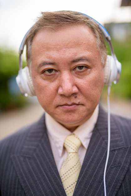 Homme d'affaires asiatique mature, écouter de la musique dans les rues surpasser