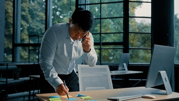 Homme d'affaires asiatique occupé homme coréen travaillant au bureau parler sur appel de consultation téléphonique multitâche