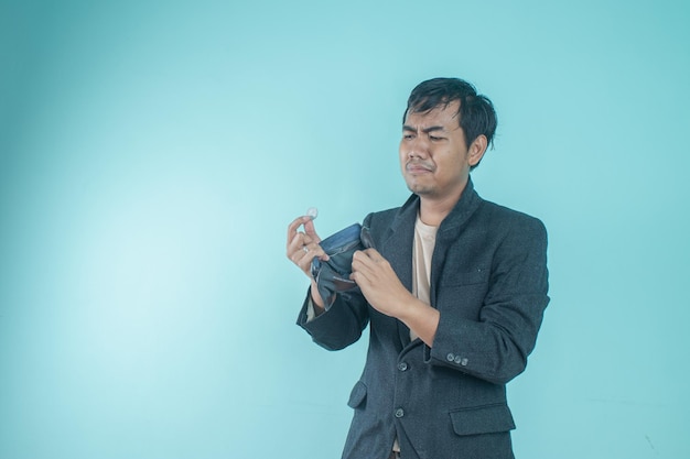 Un homme d'affaires asiatique portant un costume noir a l'air triste à cause du contenu de son portefeuille vide. Debout