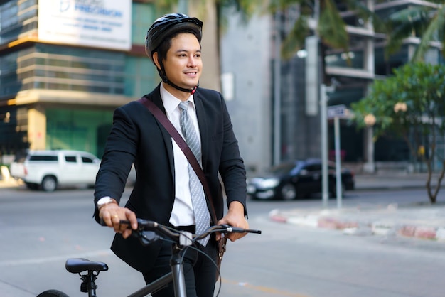 Homme d'affaires asiatique poussant son vélo de chez lui le matin se préparant à faire du vélo pour aller travailler. Transport écologique.