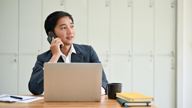 Un homme d'affaires asiatique professionnel du millénaire parle au téléphone