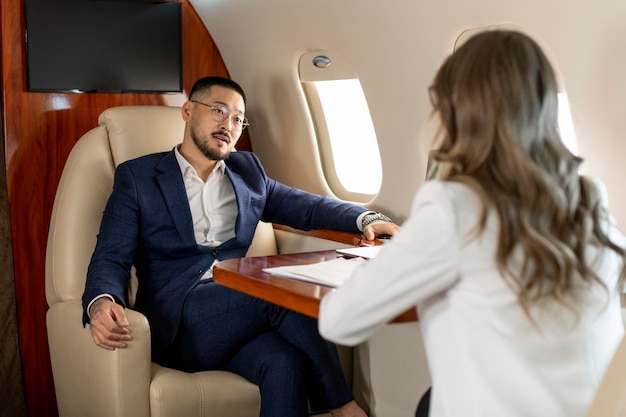 Un homme d'affaires asiatique prospère en costume à la réunion avec une femme d'affaires partenaire dans un jet privé