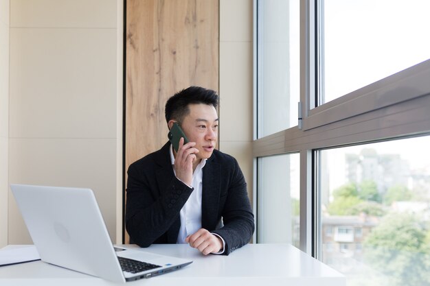 un homme d'affaires asiatique sérieux utilise un téléphone portable pour communiquer