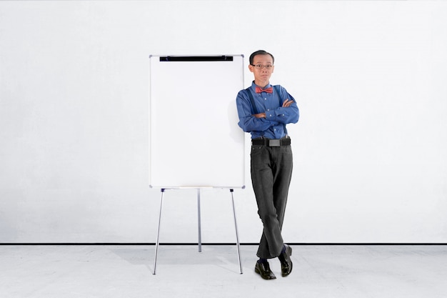 Homme d&#39;affaires asiatique souriant en costume bleu se penchant vers le tableau blanc