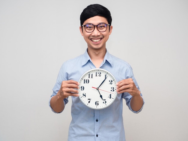 Homme d'affaires asiatique sourire heureux tenant une horloge analogique isolée